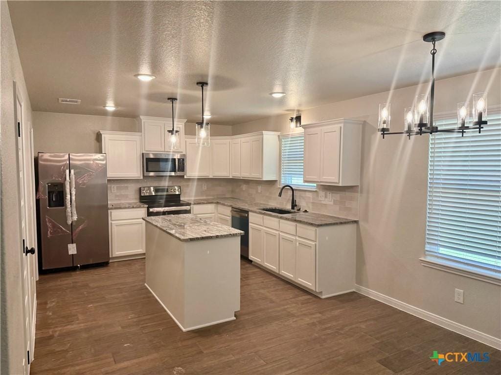kitchen featuring a sink, appliances with stainless steel finishes, a kitchen island, and dark wood finished floors