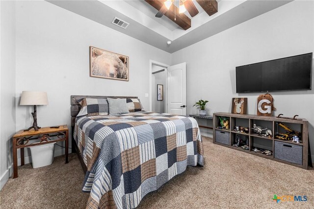 bedroom with a raised ceiling, ceiling fan, and carpet