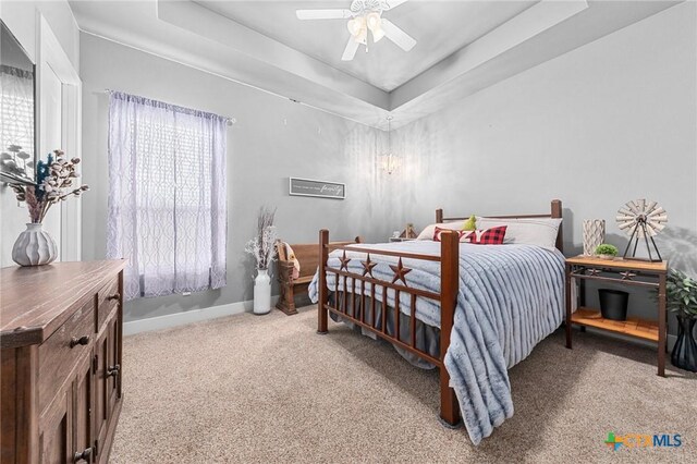 bedroom with carpet floors, a tray ceiling, and ceiling fan