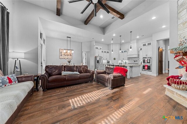 living room featuring ceiling fan with notable chandelier, beam ceiling, dark hardwood / wood-style flooring, and sink