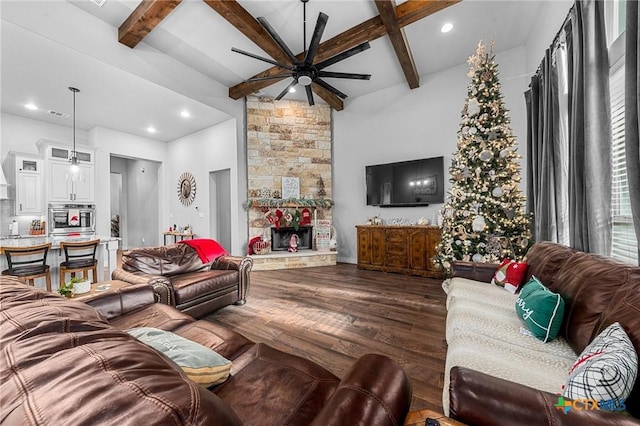 living room with ceiling fan, dark wood-type flooring, beamed ceiling, a towering ceiling, and a fireplace