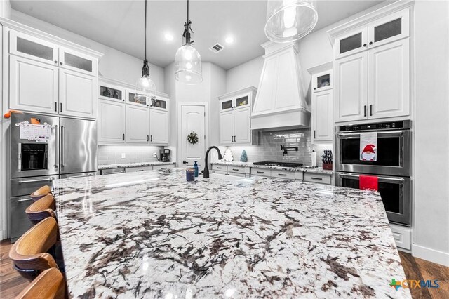 kitchen featuring white cabinets, custom range hood, backsplash, and appliances with stainless steel finishes