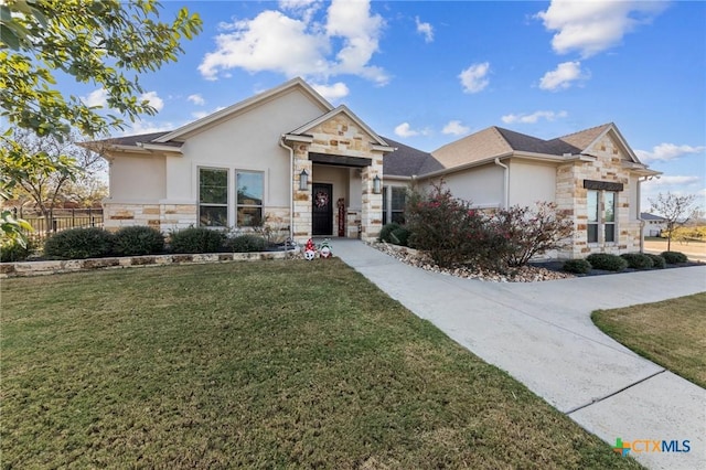 view of front of home with a front yard, stone siding, fence, and stucco siding