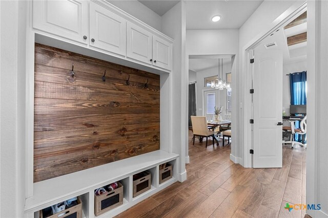 mudroom featuring wood-type flooring and an inviting chandelier