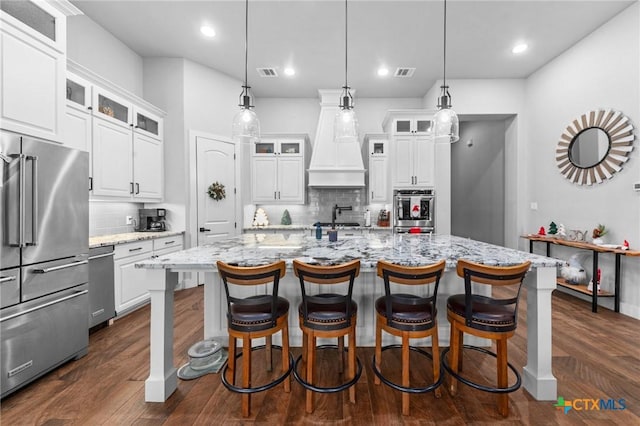 kitchen featuring a center island with sink, white cabinetry, and high quality fridge