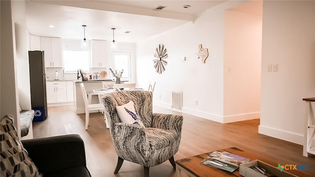 living room with visible vents, light wood-style flooring, and baseboards