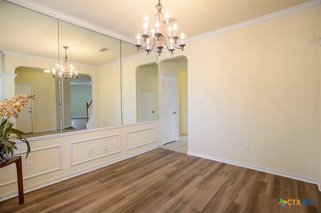 unfurnished dining area featuring crown molding, wood-type flooring, and a notable chandelier