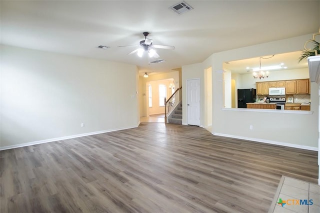 unfurnished living room featuring ceiling fan with notable chandelier and hardwood / wood-style floors