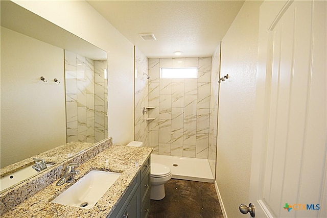 bathroom featuring vanity, toilet, a textured ceiling, and a tile shower