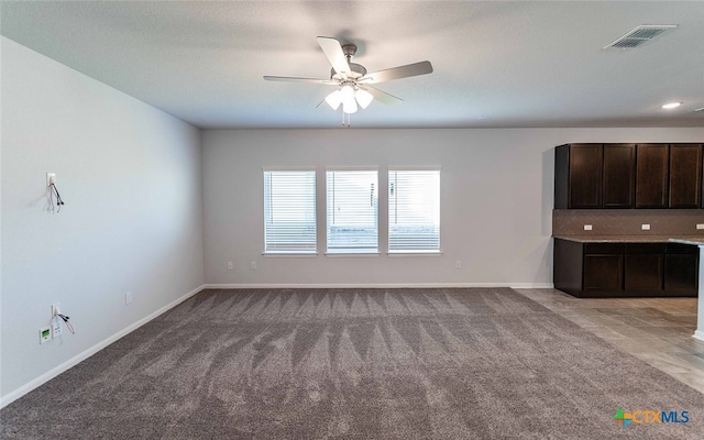 unfurnished living room featuring ceiling fan and light carpet