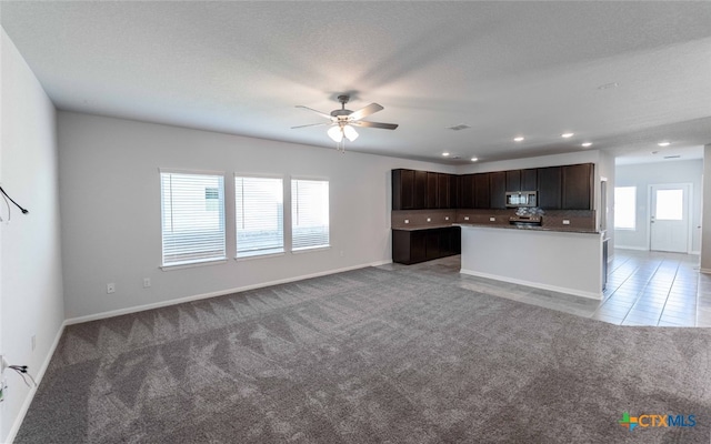 kitchen featuring dark brown cabinets, light colored carpet, ceiling fan, and a center island