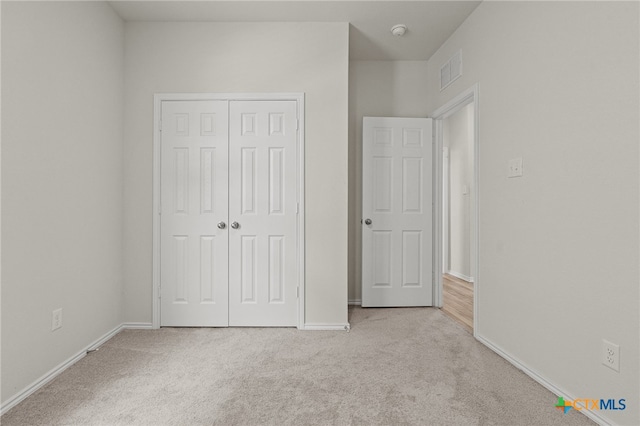 unfurnished bedroom with light colored carpet and a closet