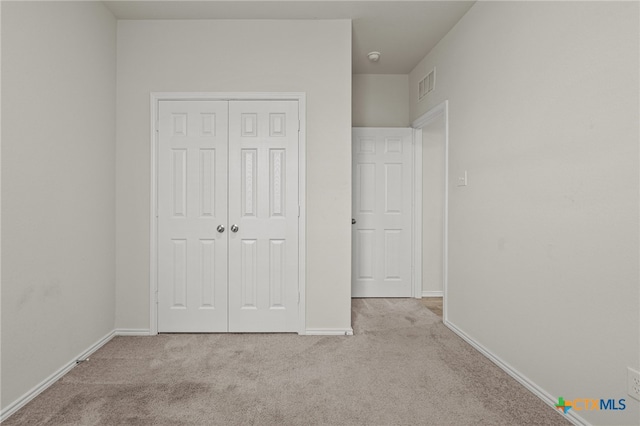 unfurnished bedroom featuring a closet and light carpet