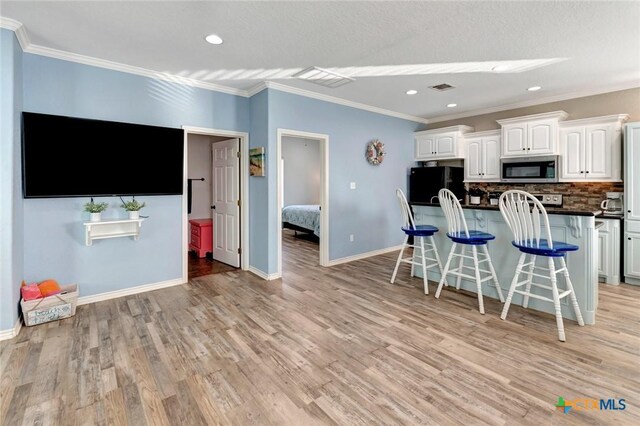 52 Fm 2031, Matagorda, TX 77457 - kitchen featuring stainless steel microwave, freestanding refrigerator, white cabinets, a kitchen breakfast bar, and dark countertops
