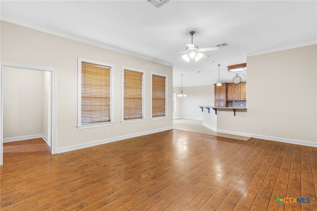 unfurnished living room featuring ceiling fan with notable chandelier, wood-type flooring, and crown molding