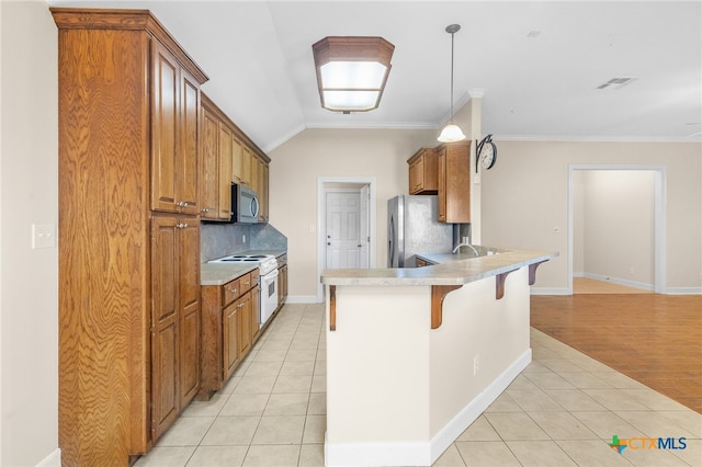 kitchen featuring light hardwood / wood-style floors, a breakfast bar, appliances with stainless steel finishes, decorative light fixtures, and lofted ceiling