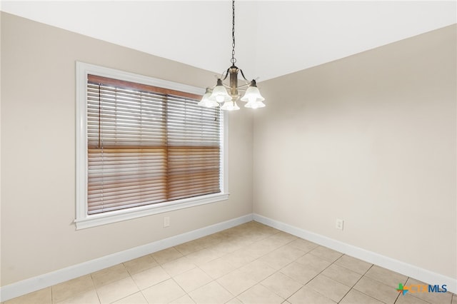 tiled spare room featuring an inviting chandelier