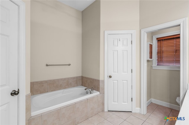 bathroom with toilet, tile patterned floors, and tiled tub