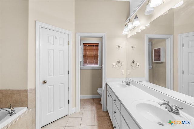 bathroom with tile patterned flooring, vanity, toilet, and a relaxing tiled tub