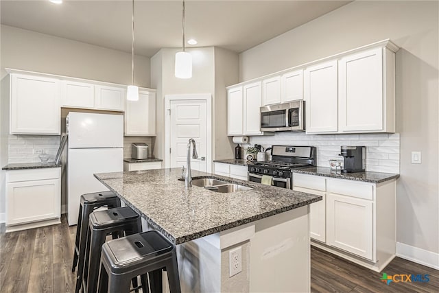 kitchen featuring sink, white cabinetry, appliances with stainless steel finishes, pendant lighting, and a kitchen island with sink