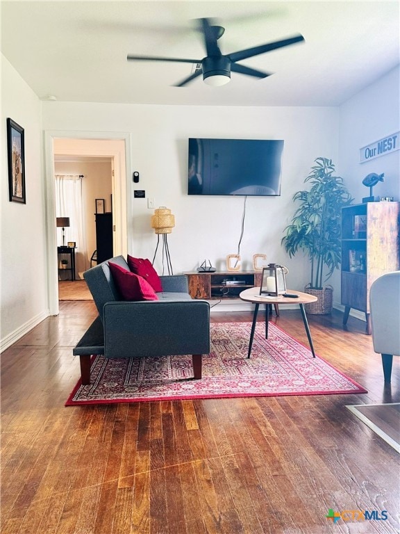 living area featuring wood finished floors, a ceiling fan, and baseboards