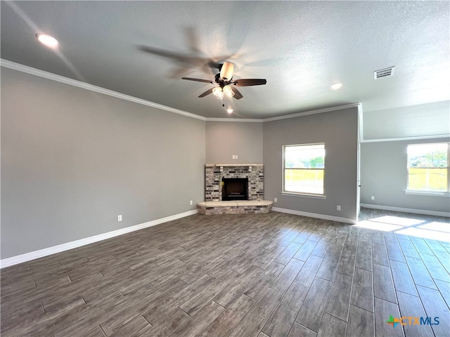 unfurnished living room featuring a brick fireplace, hardwood / wood-style floors, a textured ceiling, ornamental molding, and ceiling fan