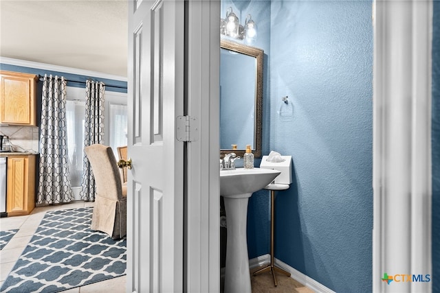 bathroom with a textured wall and baseboards