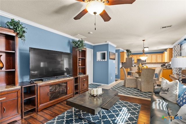 living room with dark wood finished floors, visible vents, ornamental molding, a ceiling fan, and a textured ceiling