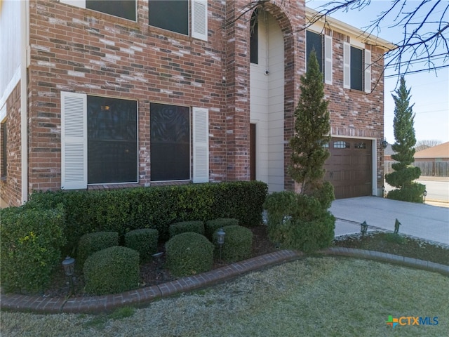 view of front facade featuring a garage, concrete driveway, and brick siding