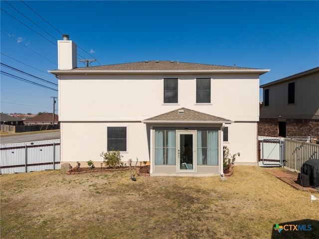 back of property with a yard, fence, a gate, and stucco siding