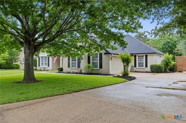 408 O W Lowrey, Salado, TX 76571 - view of front facade featuring an attached garage, concrete driveway, a front lawn, and brick siding