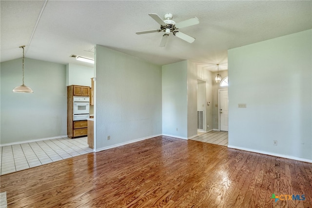 spare room featuring ceiling fan, vaulted ceiling, a textured ceiling, and light hardwood / wood-style floors