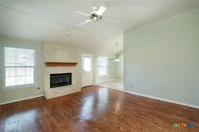 unfurnished living room featuring dark wood-type flooring, a brick fireplace, lofted ceiling, and ceiling fan