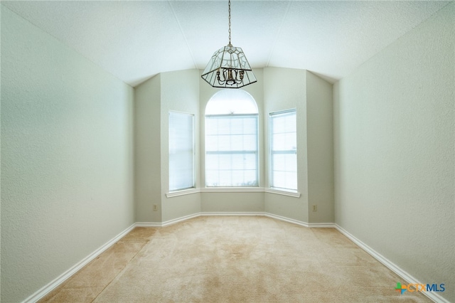 carpeted empty room featuring a chandelier and lofted ceiling