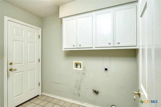 clothes washing area with washer hookup, a textured ceiling, light tile patterned floors, hookup for an electric dryer, and cabinets