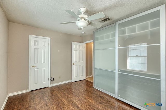 empty room featuring a textured ceiling, ceiling fan, and dark hardwood / wood-style flooring