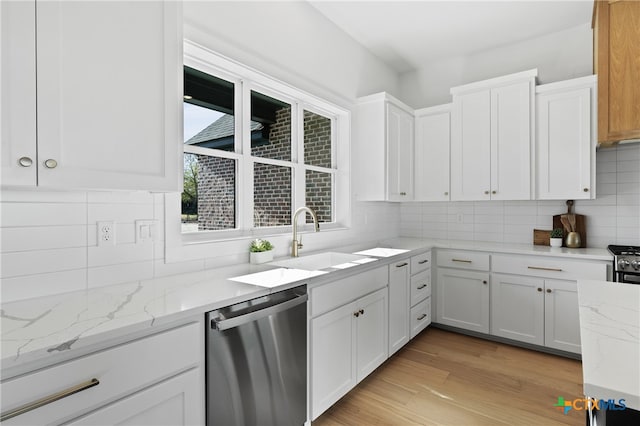 kitchen with light stone countertops, appliances with stainless steel finishes, white cabinetry, and sink