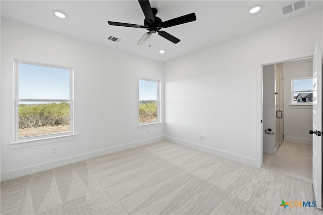 empty room featuring ceiling fan and light colored carpet