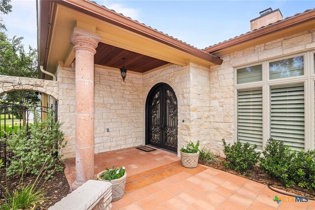 property entrance featuring stone siding, a chimney, and french doors