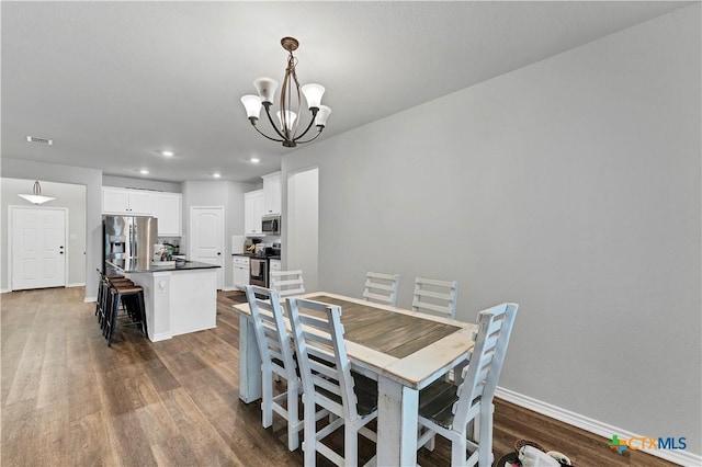 dining area with dark wood-type flooring and a chandelier