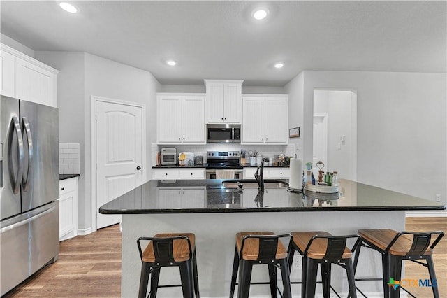 kitchen featuring stainless steel appliances, an island with sink, and white cabinets