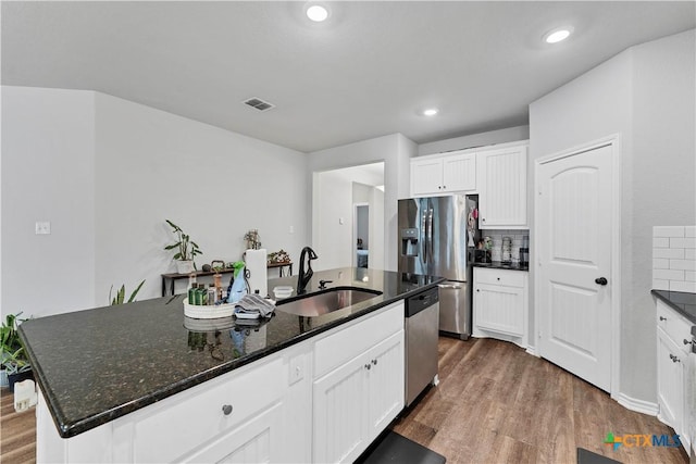 kitchen with white cabinetry, sink, stainless steel appliances, and an island with sink