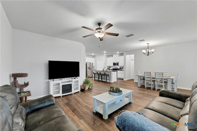 living room with hardwood / wood-style flooring and ceiling fan with notable chandelier