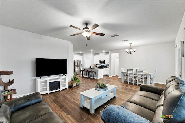 living room with wood-type flooring, sink, ceiling fan with notable chandelier, and a textured ceiling