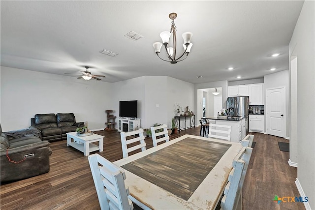 dining space featuring ceiling fan with notable chandelier and dark hardwood / wood-style flooring