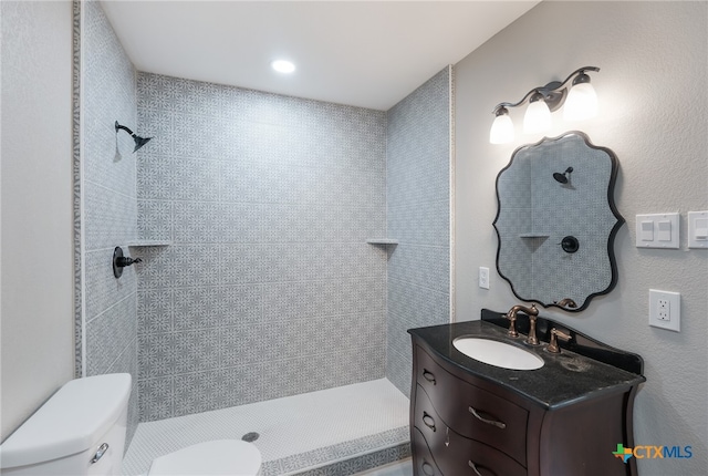 bathroom featuring toilet, vanity, and a tile shower