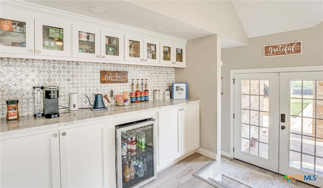 bar featuring white cabinets, lofted ceiling, light stone counters, and wine cooler