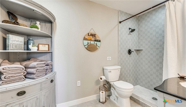 bathroom with vanity, tile patterned floors, toilet, and tiled shower