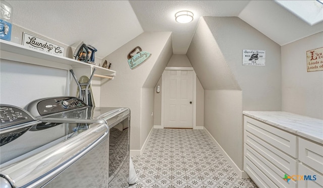 washroom featuring a skylight, a textured ceiling, and separate washer and dryer