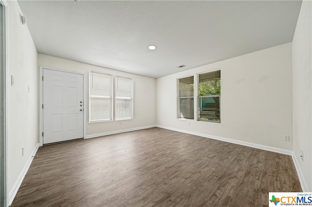 unfurnished room featuring a textured ceiling, plenty of natural light, and dark hardwood / wood-style floors